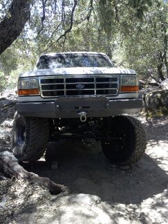 1995 Ford Bronco - A white Ford Bronco with a modified front bumper and off-road tires is seen from the front.