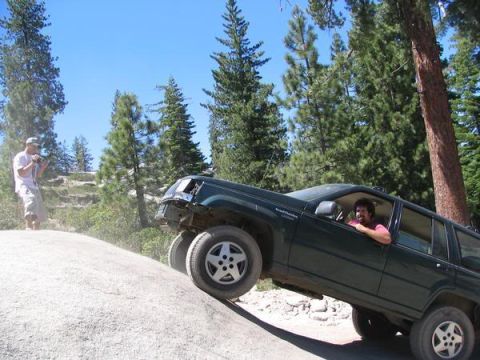 1995 Ford Bronco - An off-road enthusiast navigates a challenging rocky terrain in a dark green SUV.