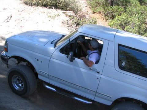 1995 Ford Bronco - A white 1995 Ford Bronco navigates an off-road trail.