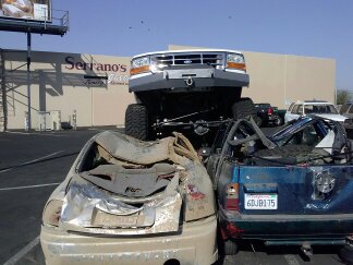 1995 Ford Bronco - A lifted 1995 Ford Bronco is parked on top of two heavily damaged vehicles.