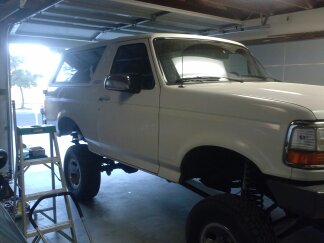 1995 Ford Bronco - White Ford Bronco in a garage, lifted for maintenance.