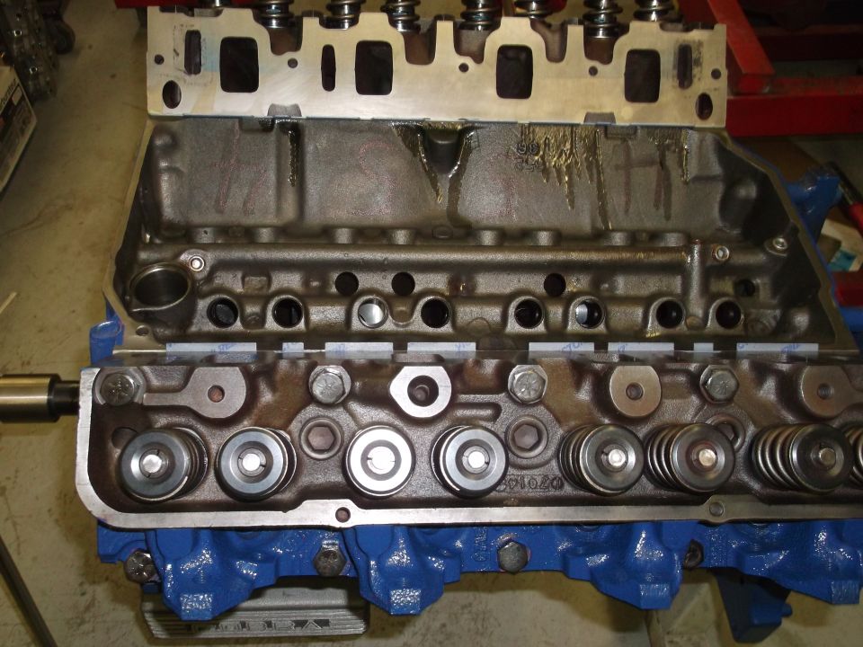 Engine block with blue paint and cylinder head assembly, showing valves and springs