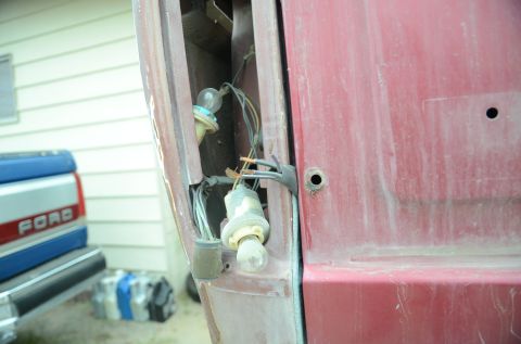 1979 Ford Bronco - The exposed wiring and bulbs of a vehicle's tail light assembly are visible, with another truck in the background.