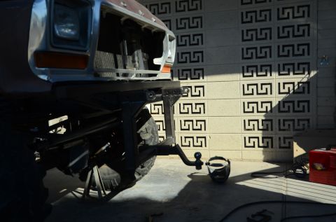 1979 Ford Bronco - The front of a vehicle, possibly a 1979 Ford Bronco, is shown with a hitch assembly and a welding mask nearby.