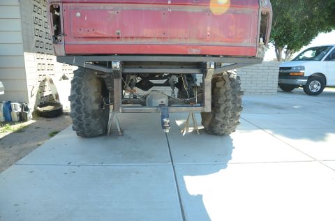 1979 Ford Bronco - Rear view of a red pickup truck undergoing modifications, with a custom hitch assembly visible.