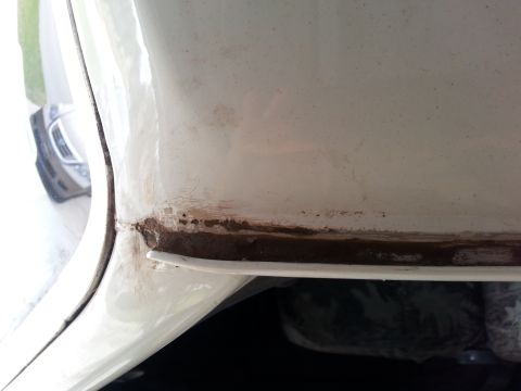 1992 Ford Bronco - Rust is visible on the lower body panel of a white vehicle, with another vehicle in the background.