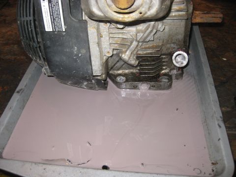 2006 Honda RANCHER - Engine oil is draining into a pan from the removed drain plug.