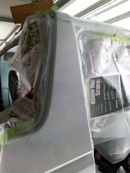 1992 Ford Bronco - A vehicle body panel is masked and covered with newspaper, indicating repair work is in progress.