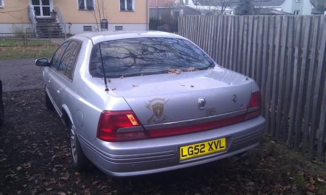 Silver sedan rear view with yellow license plate LG52 XVL and a decal on the trunk