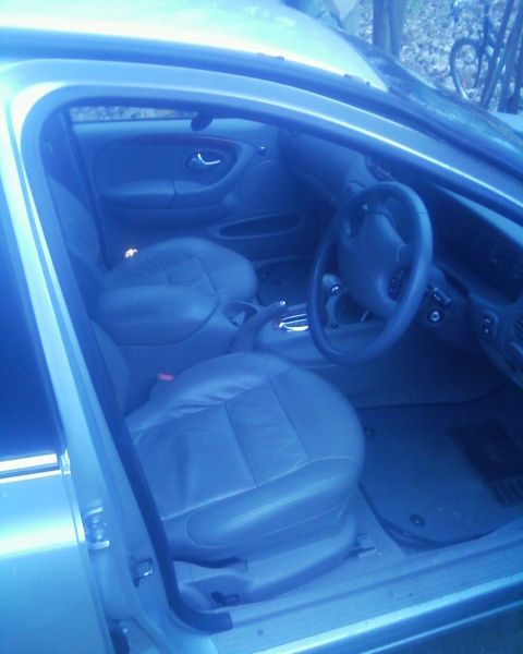 1999 Ford Fairlane - The interior of a car shows leather seats and the driver's side controls, with a watermark at the bottom.