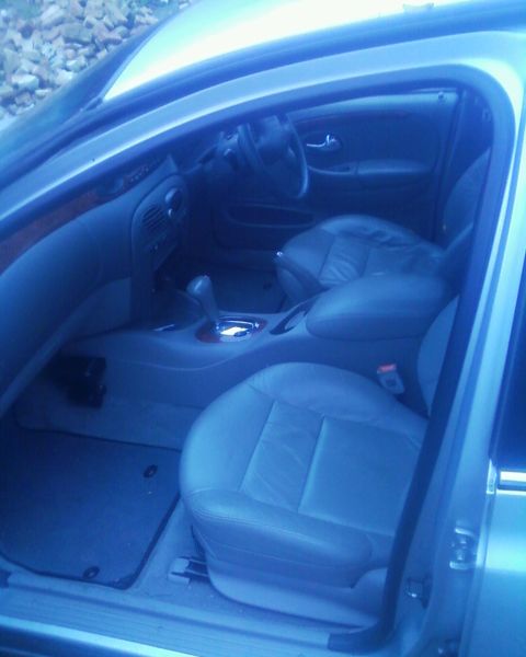 1999 Ford Fairlane - The interior of a car is visible, showing the front seats, dashboard, and gear shifter.