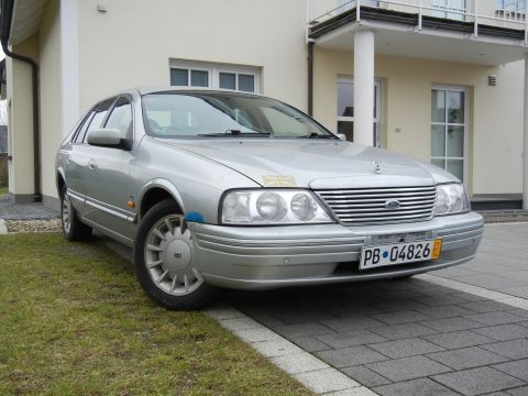 1999 Ford Fairlane - A silver sedan with a distinctive grille is parked outside a modern house.