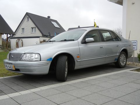 1999 Ford Fairlane - This silver sedan, possibly a Ford Fairlane, shows some cosmetic damage with blue paint marks on the front fender.