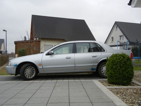 1999 Ford Fairlane - Silver 1999 Ford Fairlane sedan parked on a paved driveway with houses in the background.