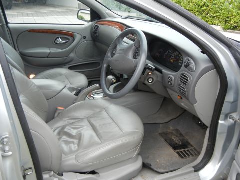 1999 Ford Fairlane - The interior of a 1999 Ford Fairlane features grey leather seats and a wood-trimmed dashboard.