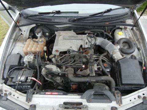 1999 Ford Fairlane - The engine bay of a car is shown with the hood open, revealing the engine components and battery.