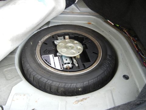 1999 Ford Fairlane - The spare tire and jack are visible in the trunk of a vehicle.