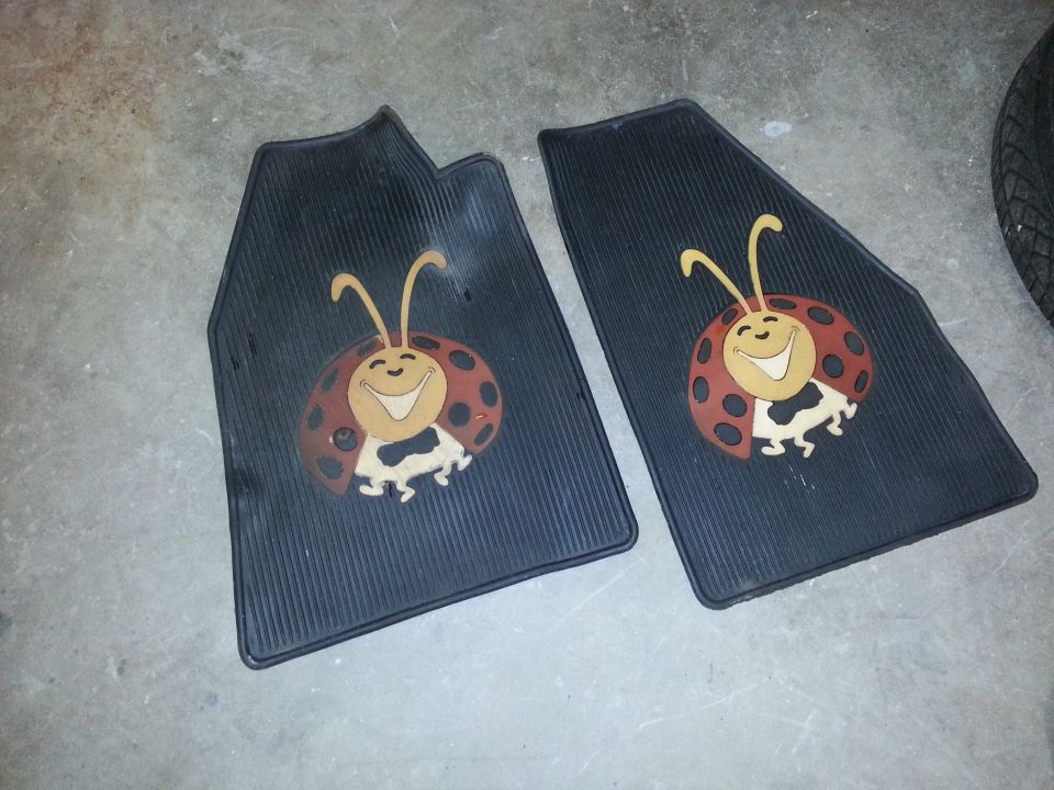 Two black rubber floor mats, each with a cartoon ladybug graphic. One mat is partially visible on the right