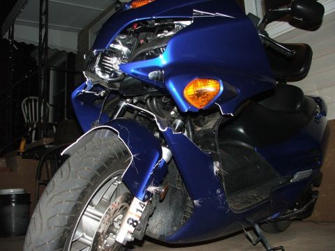 2006 Honda Reflex - Damaged blue scooter front end, showing broken fairing and turn signal.