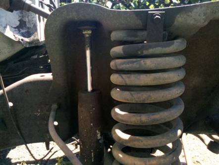 1982 Ford Bronco - Close-up of a front suspension coil spring and shock absorber, likely from an older vehicle.