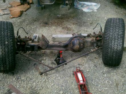 1982 Ford Bronco - Front axle assembly with tires, supported by jack stands, with a "Supermotors.net" watermark at the bottom.