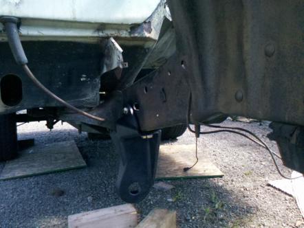 1982 Ford Bronco - The underside of a vehicle shows its frame and suspension components, with some rust visible.