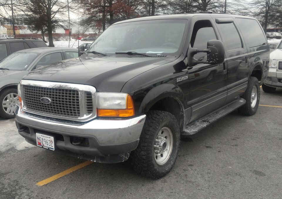 Black Ford Excursion SUV parked in a lot, front 3/4 view. Visible "EXCURSION" badge on fender
