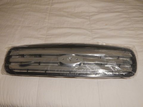2003 Ford Crown Victoria - black-and-chrome horizontal-bar automotive front grille with a central oval emblem mount, sealed in plastic on a white sheet.