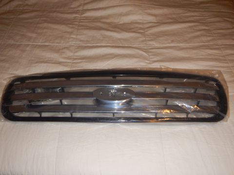 2003 Ford Crown Victoria - Front view of a black-framed grille with chrome horizontal bars and a center Ford oval, wrapped in plastic.