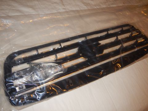 2003 Ford Crown Victoria - Angled rear view of a black grille backing with molded mounting tabs and clips, under plastic wrap.