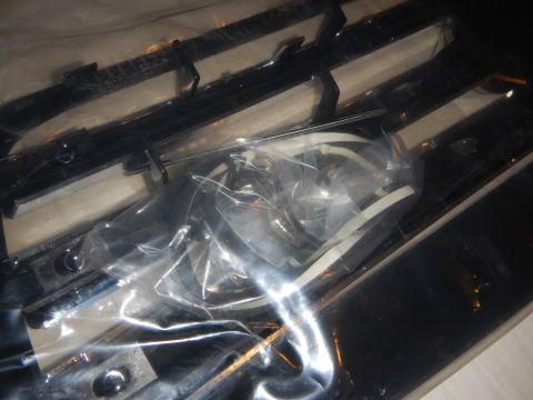 2003 Ford Crown Victoria - Close-up of the dark rear of a grille with a plastic bag of mounting screws and clips resting on it.