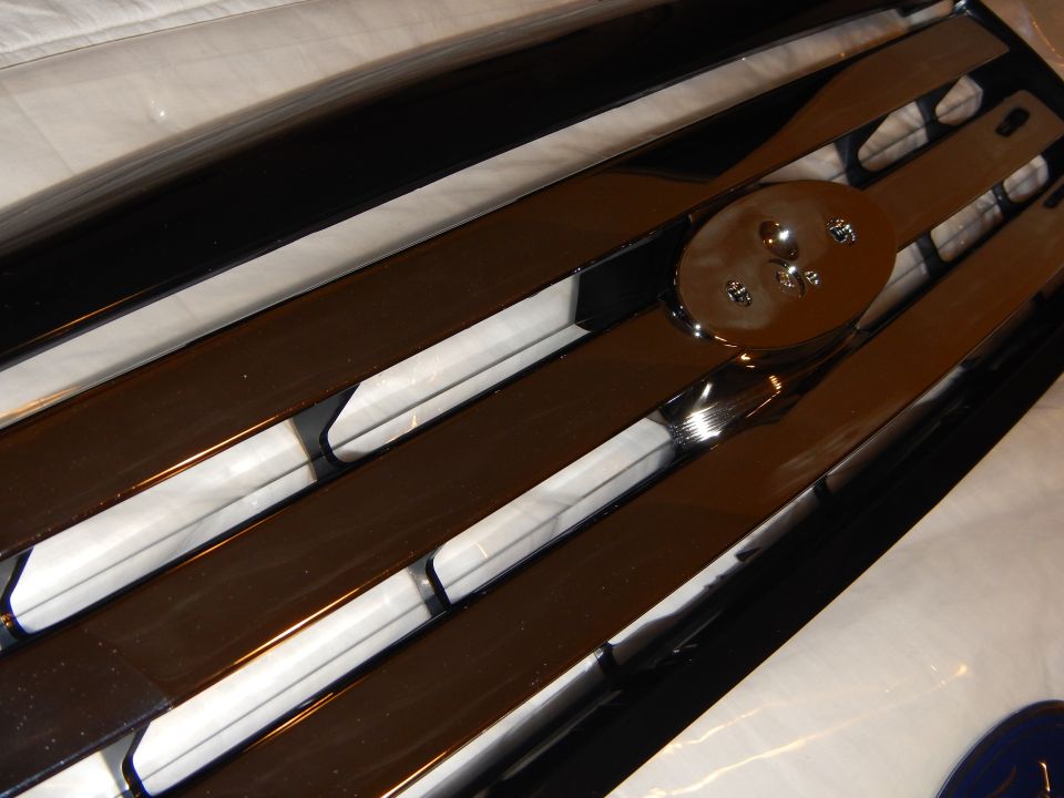 Angled close-up of grille oval mount with chrome bars and white backing strips