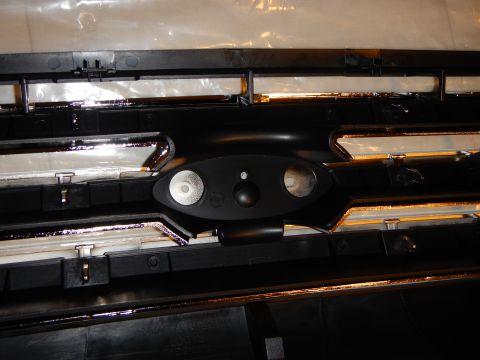 2003 Ford Crown Victoria - Close-up of the rear of a grille's oval emblem mount, showing two outer stud holes and a center hole.