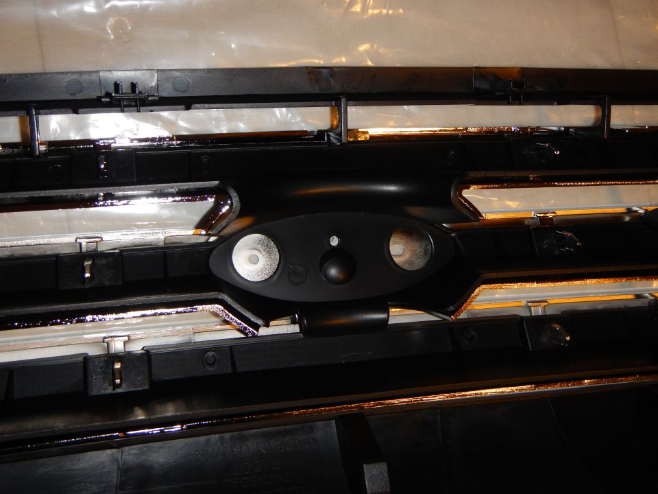 Close-up of grille rear oval emblem mount with two stud holes and a center hole