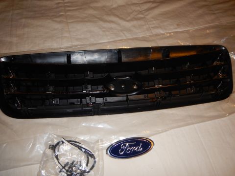 2003 Ford Crown Victoria - Rear view of a black-and-chrome grille with mounting clips, a hardware bag, and a blue Ford oval emblem.