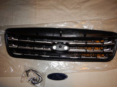 2003 Ford Crown Victoria - Rear of a black-and-chrome grille embossed 'Made in Taiwan' with a hardware bag and blue Ford oval emblem.