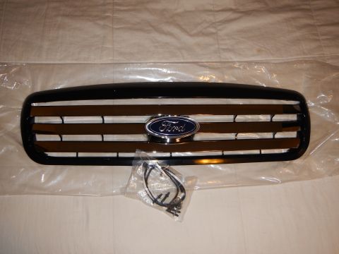 2003 Ford Crown Victoria - black Ford front grille with chrome accents and blue oval badge laid on plastic wrap, accompanied by a bagged harness and mounting screws.