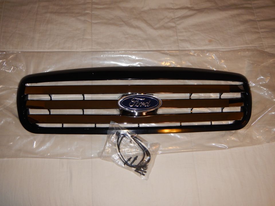 Black Ford grille with chrome trim and blue oval emblem with parts bag