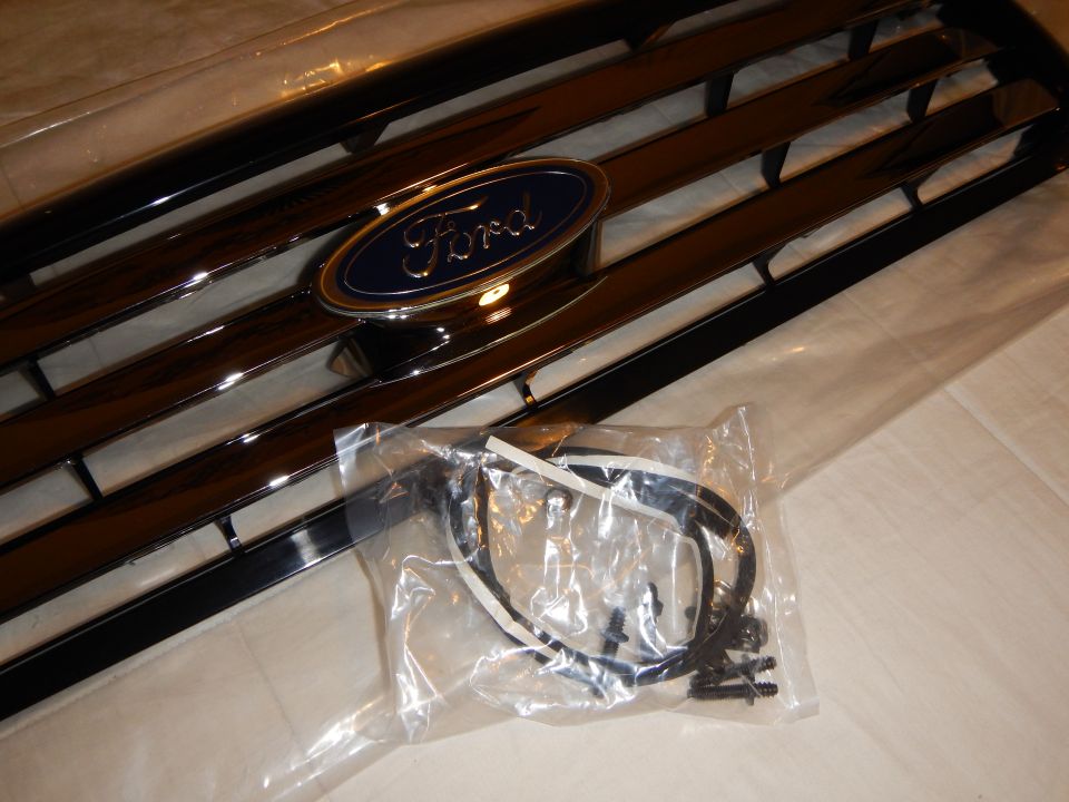 Angled close-up of black Ford grille blue oval emblem and bagged harness