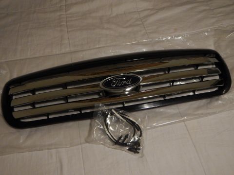 2003 Ford Crown Victoria - black Ford front grille with chrome horizontal bars and a centered blue oval emblem, shown with a small bagged wiring harness.