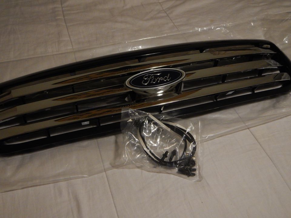 Angled view of black Ford grille with chrome trim and blue oval badge