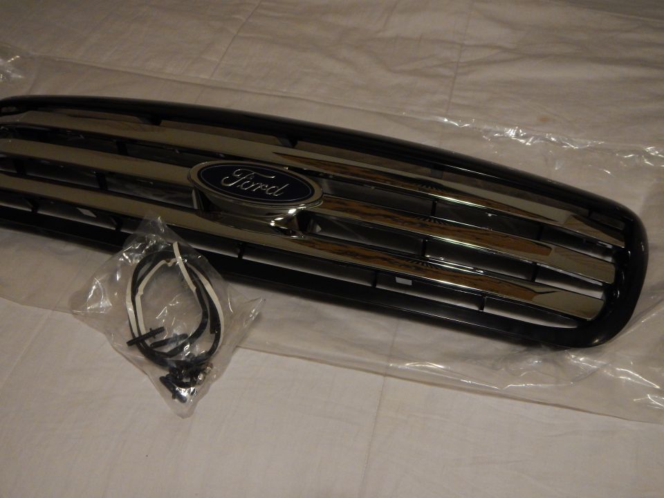 Close angled view of black Ford grille blue oval emblem and chrome bars