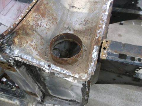 1967 Ford Mustang - Close-up view of a heavily rusted vehicle chassis, revealing structural components and a circular metal insert.