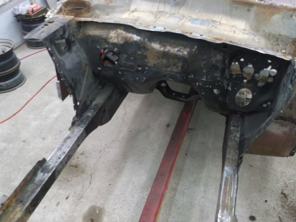 Car's firewall and frame rails, appears to be undergoing restoration or repair. Some parts are missing