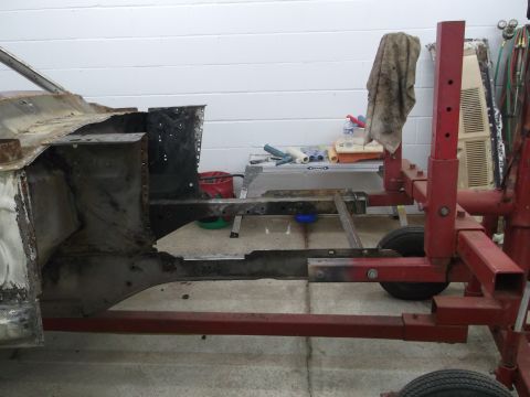 1967 Ford Mustang - The frame of a 1967 Ford Mustang is shown on a red metal stand, likely undergoing restoration.