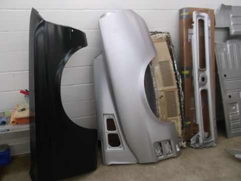 1967 Ford Mustang - Car body parts including fenders are stored indoors against a brick wall.