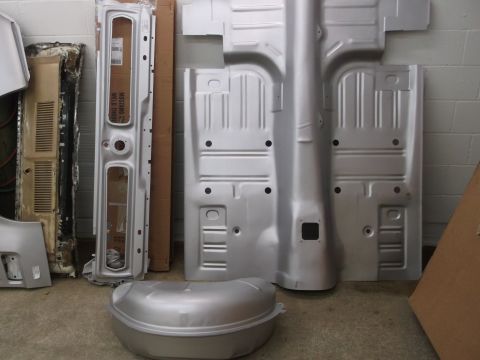 1967 Ford Mustang - Various car body panels and a spare tire well are laid out on the floor, some showing text.