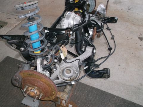 1967 Ford Mustang - A disassembled rear axle assembly, showing suspension components and brake parts, is shown on a stand.