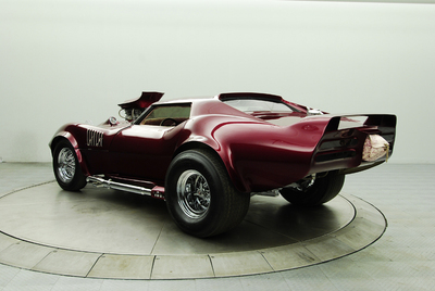 1976 Chevrolet Corvette - This customized 1976 Chevrolet Corvette features a prominent spoiler and an exposed engine, viewed from the rear three-quarter angle.