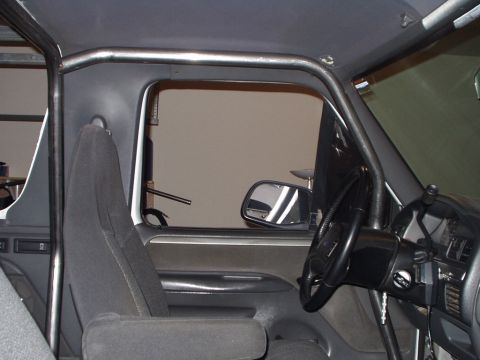1993 Ford Bronco - The interior of a vehicle is shown, a prominent roll cage structure and the driver's side controls.